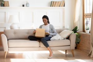 Woman holding box on lap while sitting on couch