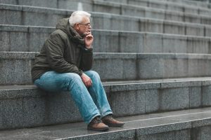 Older man sitting on stone steps thinking