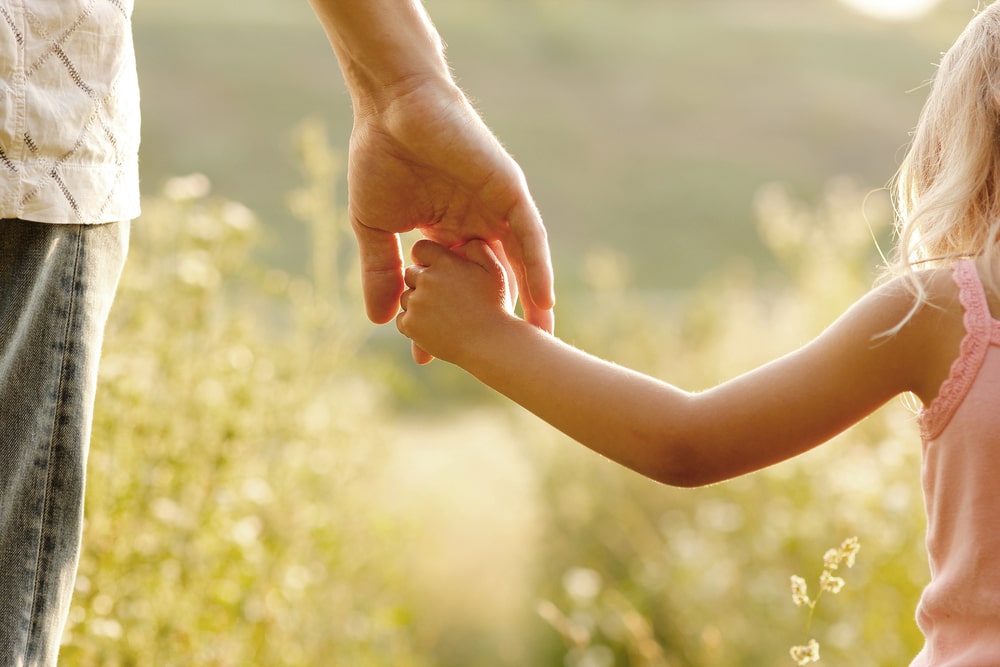 Father holding daughter's hand as they walk outside