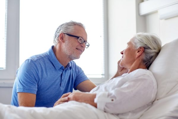 Husband sitting next to wife in hospital bed