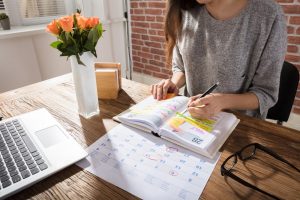 Woman writing on a calendar, outlining her routine for the week