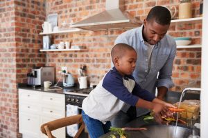 Father and young son washing a carrot as they prepare a meal