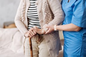 Home health nurse helping woman walk across room