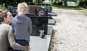 Mother and young son paying respects at a cemetery