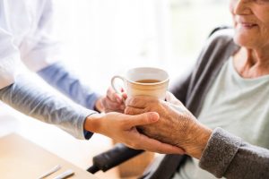 At home nurse giving cup of tea to elderly woman