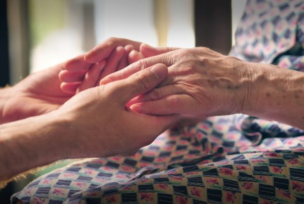 Younger person holding older person's hands in a comforting way