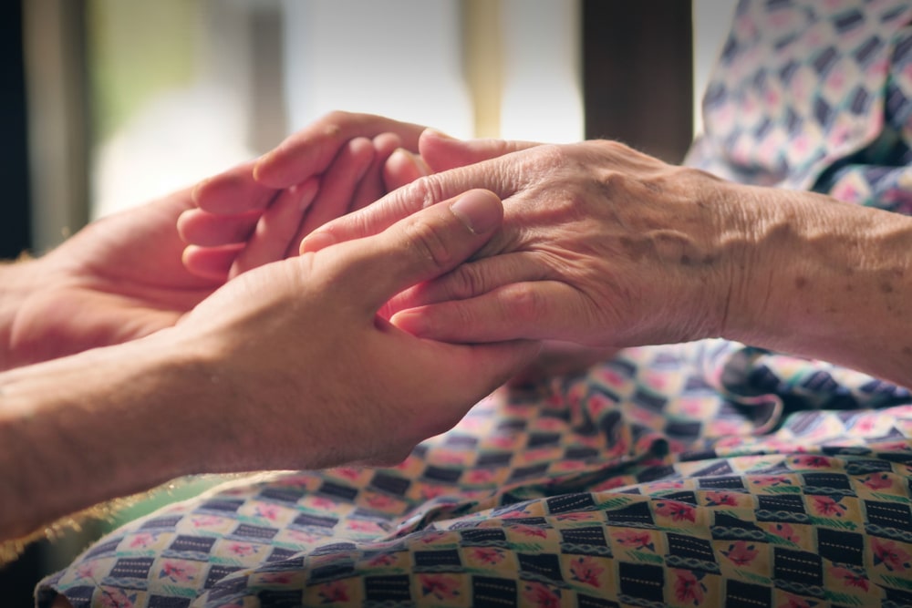 Younger person holding older person's hands in a comforting way