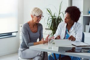 Older woman at medical appointment, talking with female doctor who is listening intently