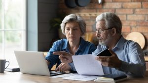 Man and woman sitting at a table reviewing documents, laptop lying on table