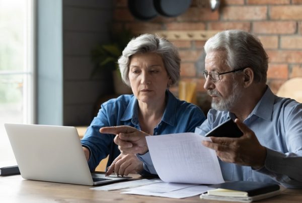 Man and woman sitting at a table reviewing documents, laptop lying on table