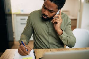 Man on phone asking about insurance, writing down answers