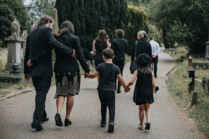 Family wearing black as they walk through cemetery