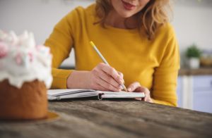 Woman sitting at table as she writes in a personal notebook