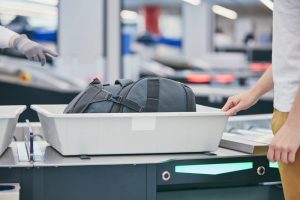 Shows man going through airport security with carry on bag