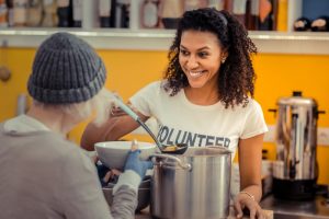 Shows young woman serving at a soup kitchen