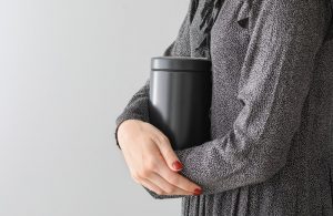 Shows a woman holding an urn clos