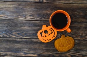 Shows an orange coffee mug and Halloween cookies