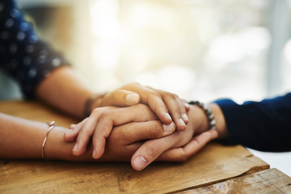 Focus on a pair of hands, one pair holding the other in a comforting way