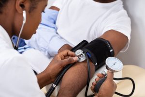 Shows man getting blood pressure taken as part of health check-up