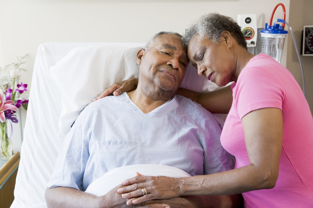 Shows a loving family member sitting with a patient at a hospital