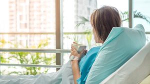 Shows woman sitting in a hospital bed receiving care