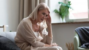Shows woman sitting on couch worrying