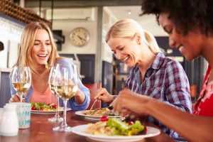 Shows three women eating dinner together and having fun