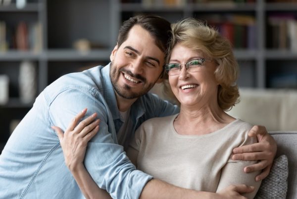 Adult son hugging his mother, both smiling