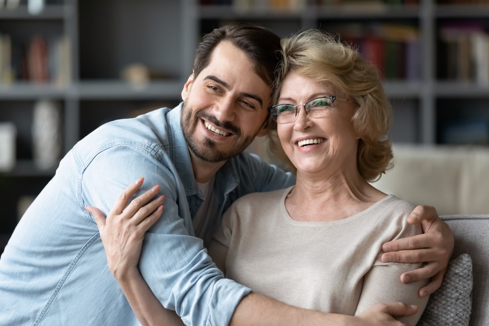 Adult son hugging his mother, both smiling