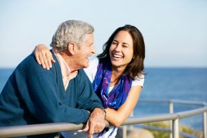 Father with adult daughter, talking and smiling while outside near the water