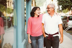 Father and daughter walking on the sidewalk, laughing