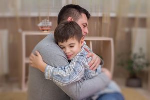 Dad hugging young son at home