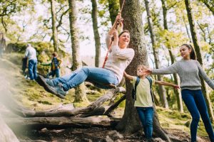 happy family in the woods swinging on tire swing