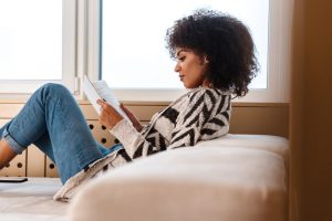 Young woman in black and white sweater sitting down and reading a book