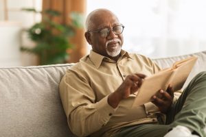 Older man sitting on comfortable couch, reading a book