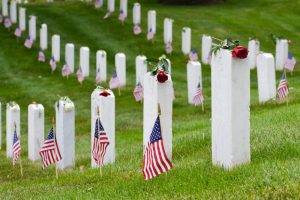 Well-kept headstones with flags and roses in a green national veteran cemetery