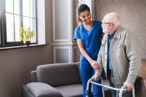 Female nurse helping elderly man with walker