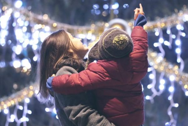 mother holding son looking at Christmas lights