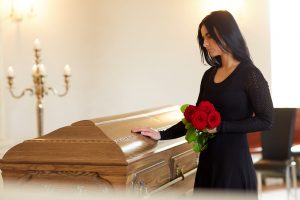 Woman wearing black standing next to a casket during a service