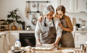 Mom and adult daughter making cookies in the kitchen together, daughter learning from mother