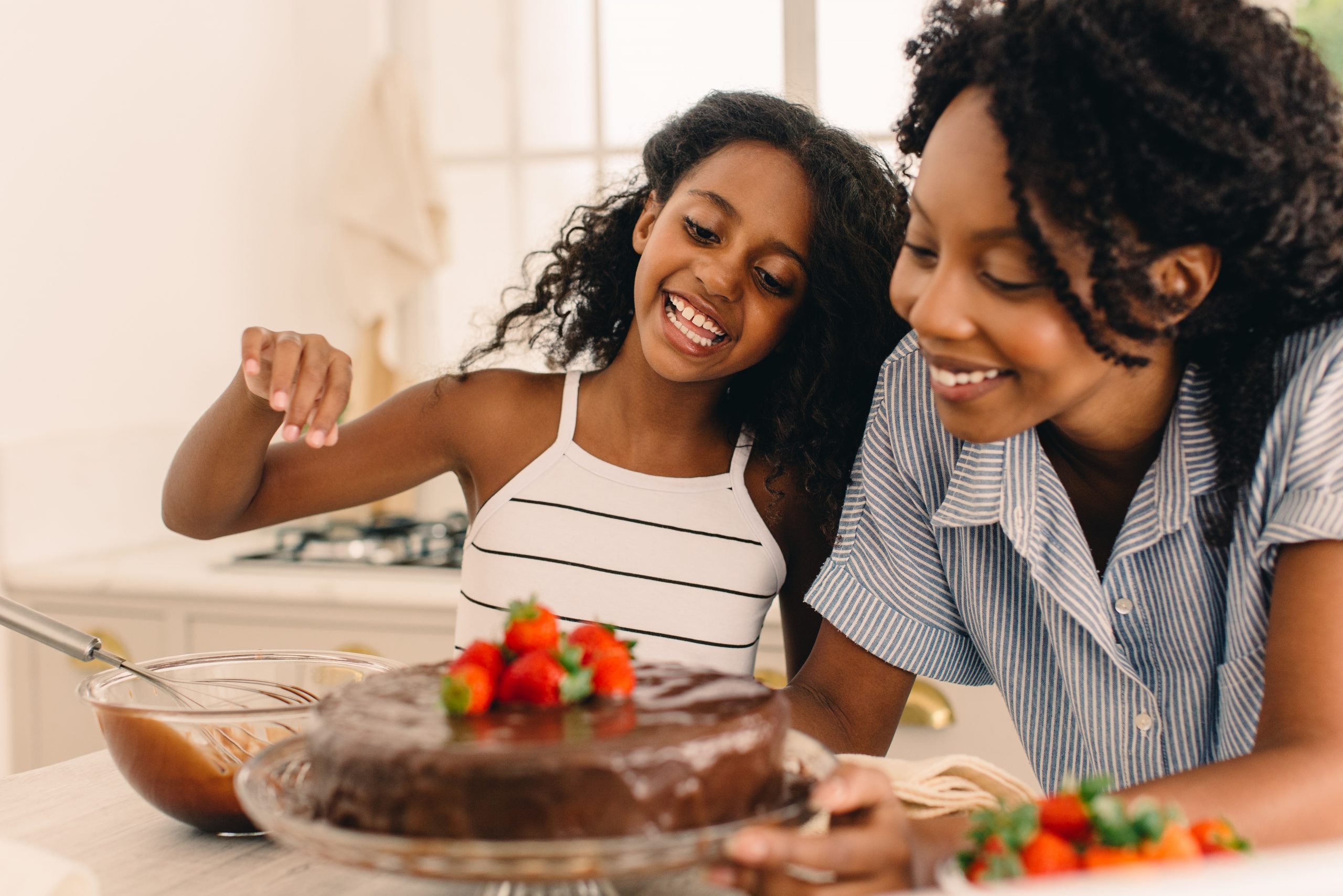 Girl with mother preparing cake in kitchen.