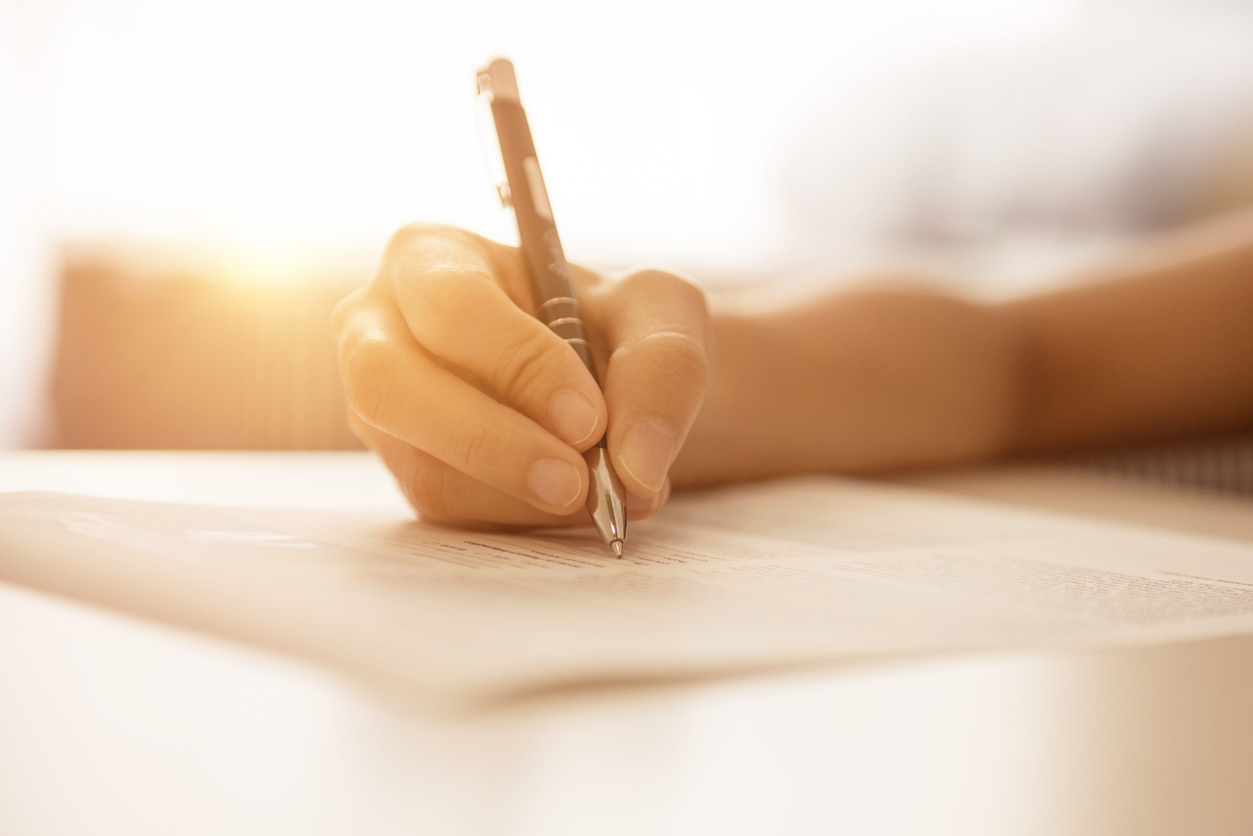 Woman hand writing on paper in office.