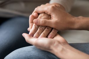 Close up young woman holding female hand of older mother, caring adult grown up daughter supporting and comforting mature mum, expressing love, two generations trusted relations