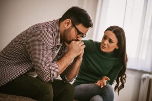 man and woman sitting on couch, woman comforting man