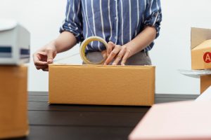 Woman taping a packing box shut