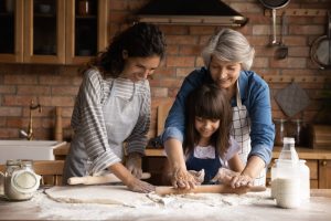 woman and daughter helping senior woman bake