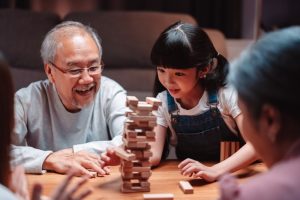 young girl and senior man playing game with blocks