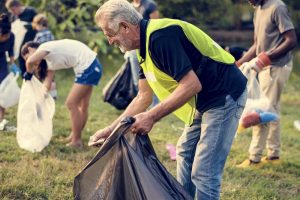 senior man volunteering and picking up trash