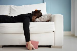 Woman laying face down on couch, feeling exhausted