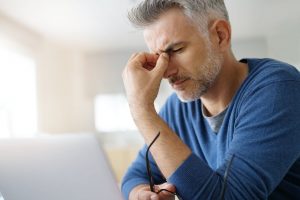 Middle-aged man pinching the bridge of his nose as he deals with a headache